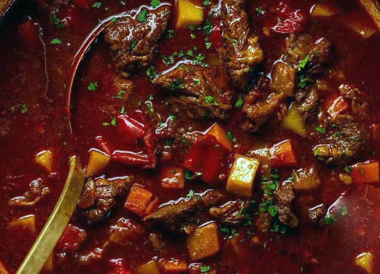 paprika coloured goulash soup in a stock pot with a spoon