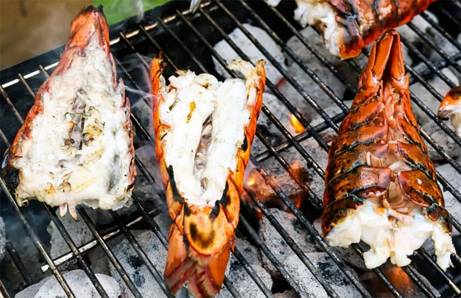 split spiny lobster tails cooking on a barbecue