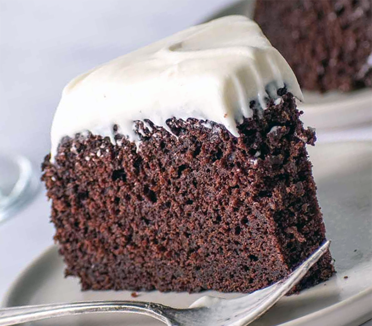 slice of porter sponge cake topped with irish cream icing on a plate with a fork