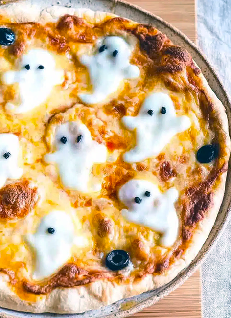 cheese pizza decorated with cheese ghosts that have pieces of black olives for eyes