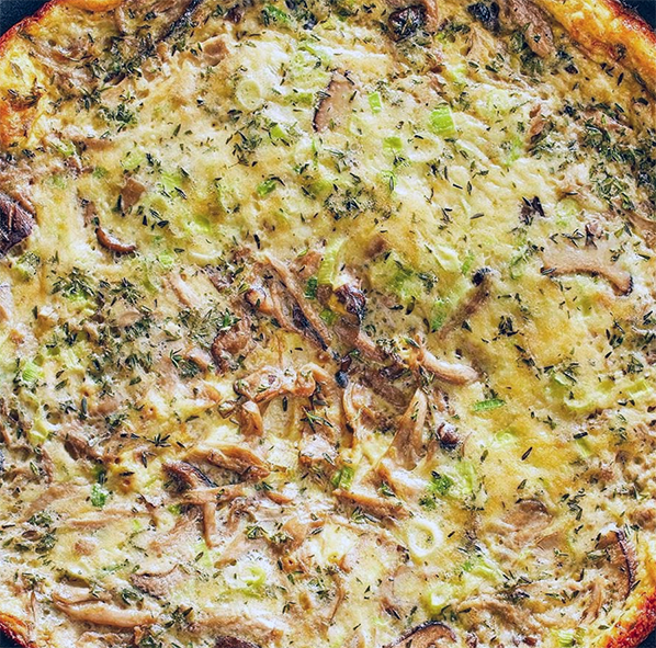 frittata containing sliced hedgehog fungus cooking in a cast iron skillet
