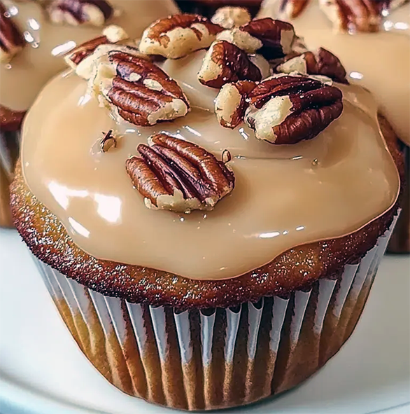honey pecan spread cupcakes topped with honey pecan icing and chopped pecans in a paper case
