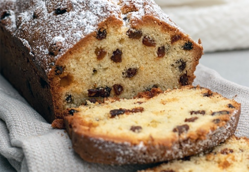 Irish rink cake with currants and almonds served on a cloth with one slice removed to show the inside