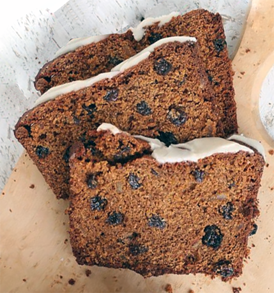 three iced slices of fruited Irish spice bread on a wooden chopping board