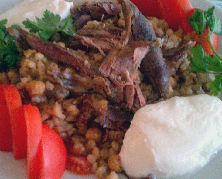 lamb and farro stew served on a plate with sour cream and tomatoes