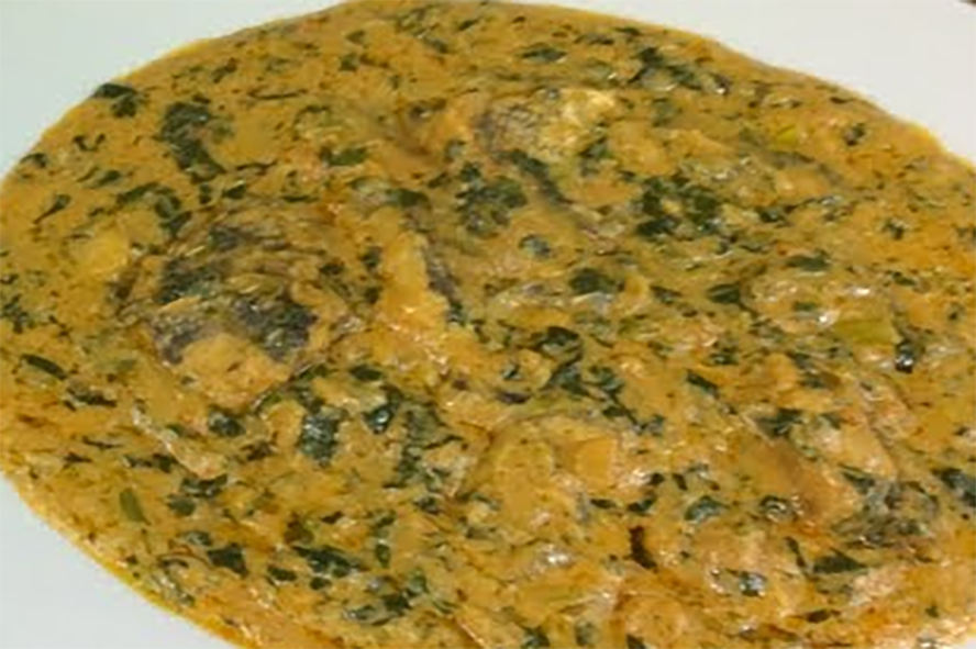 flaked fish in a peanut butter and hidjihi leaf sauce served on a plate