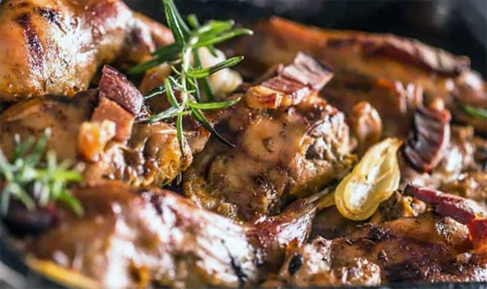 rabbit in a metal roasting tin with rosemary