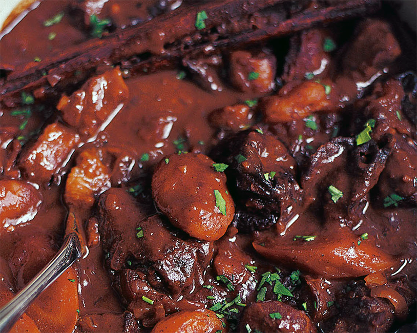 stew of lamb, apricots and prunes in a red wine base in a casserole dish