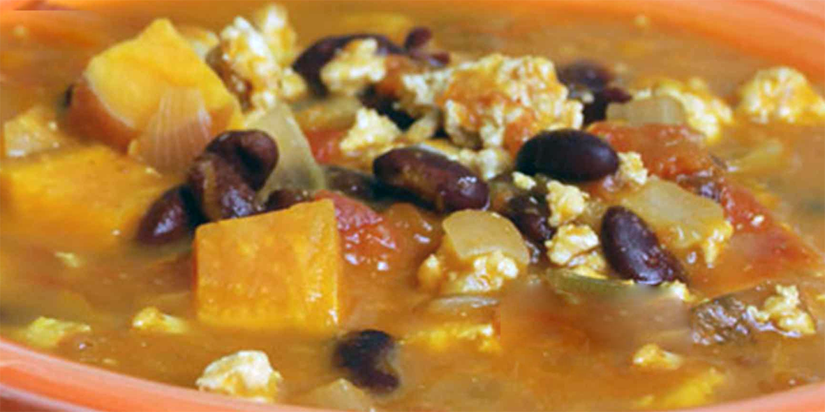 soup of pumpkin, sweet potato and beans in an earthenware bowl with feta