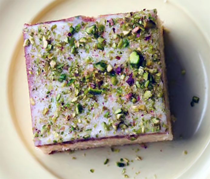 square slice of lemon pistachio snacking cake on a yellow plate
