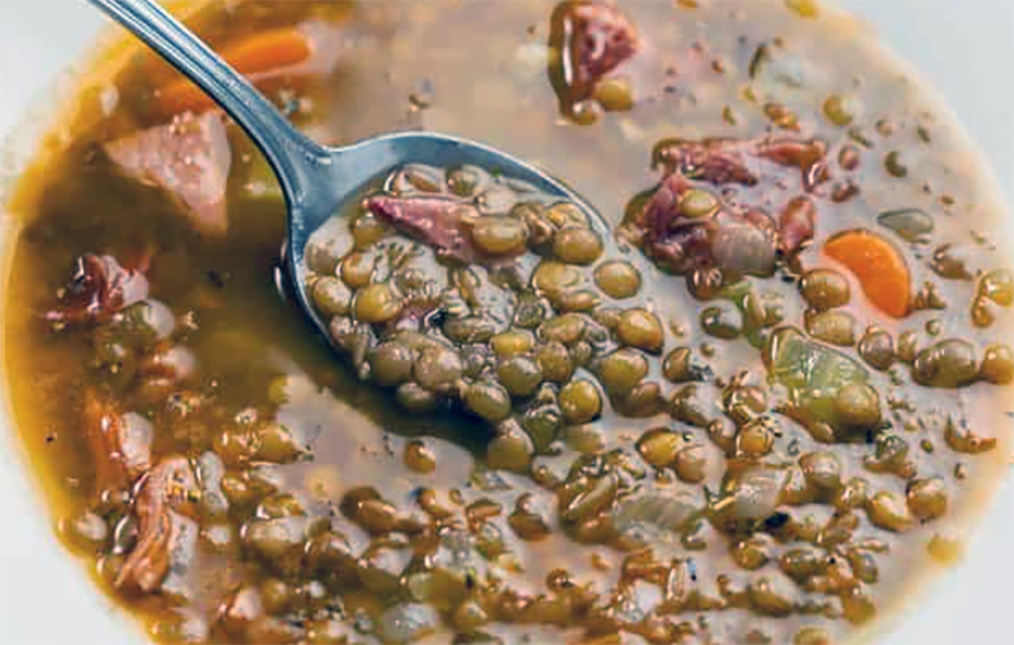 lentil soup in ham stock in a white bowl with a spoon
