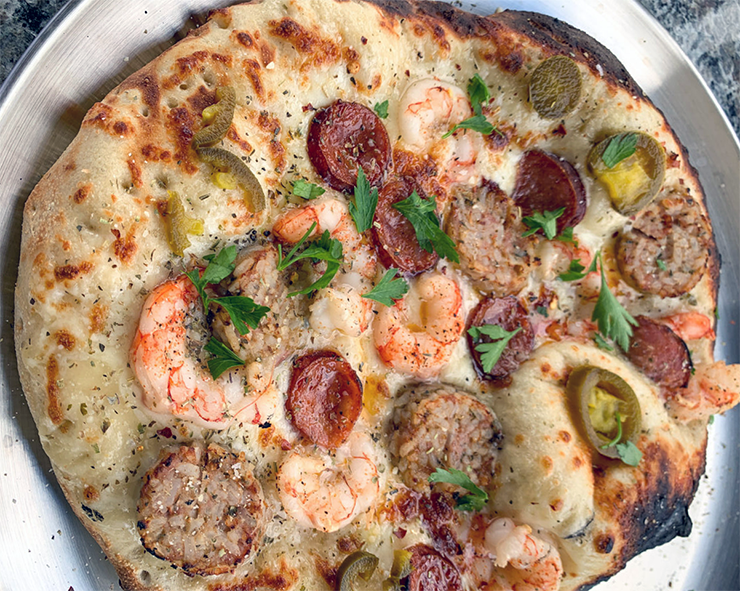 cajun pizza with sausage and crayfish tails on a metal serving dish