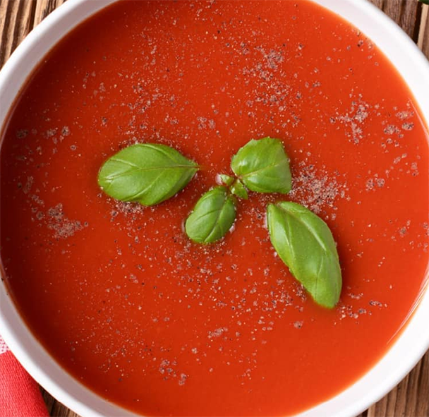 love apple (tomato) soup served in a bowl with a sprig of basil