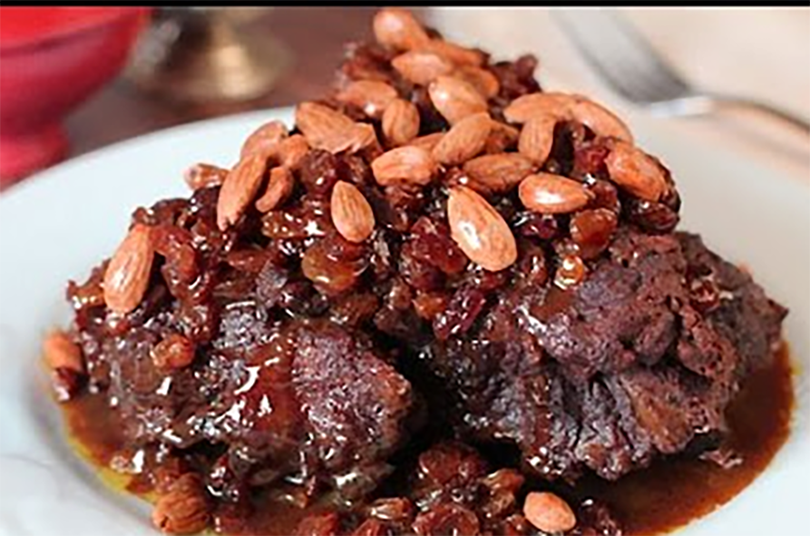 M'rouiza tagine of lamb with sultanas and honey topped with almonds on a plate