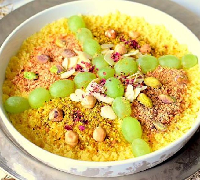 masfouf served in a bowl garnished with almonds, pine nuts, raisins and seedless grapes