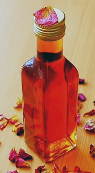 bottle of rose petal vinegar surrounded by rose petals