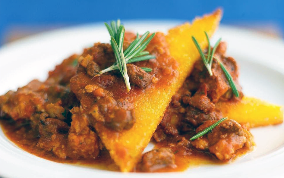 Fried polenta served with Italian sausage in a tomato sauce