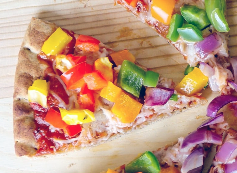 pizza topped with mixed bell peppers, red onion and pine nuts