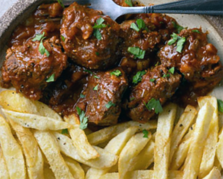 stewed beef garnished with flat-leaf parsley served with fried potatoes
