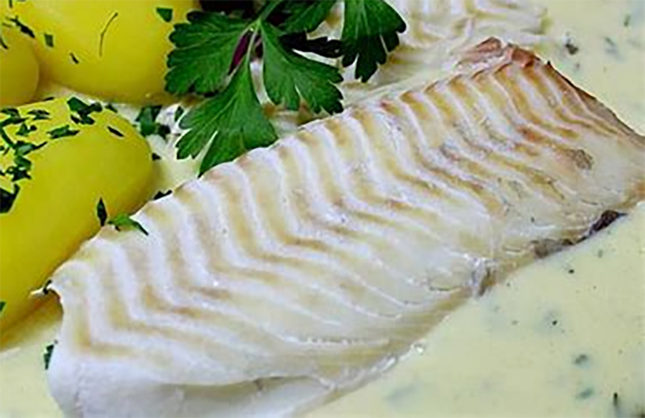boiled haddock served with parsley sauce and potatoes