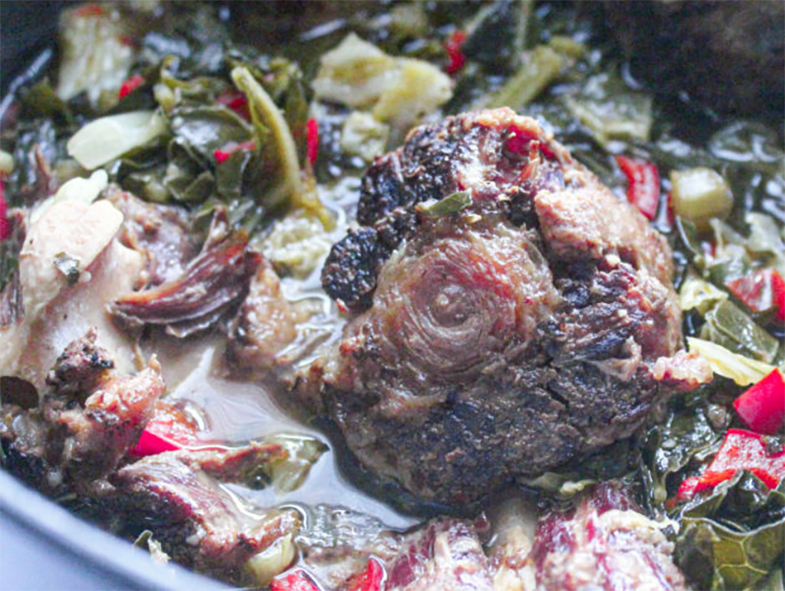 barbecued oxtail stewed with collard greens and chilli pieces in a pot