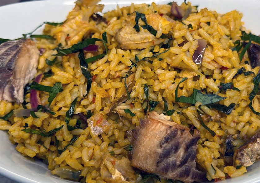 nigerian concoction rice with smoked fish and shredded african blue basil served on a plate