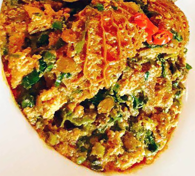 egusi and cocoyam leaf soup with honeycomb tripe on a plate