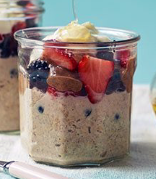 overnight oats in a glass jar served topped with fruit, nut butter and a drizzle of honey