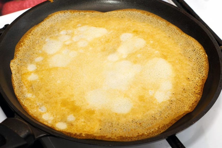 thin pancake dry frying in a heavy pan