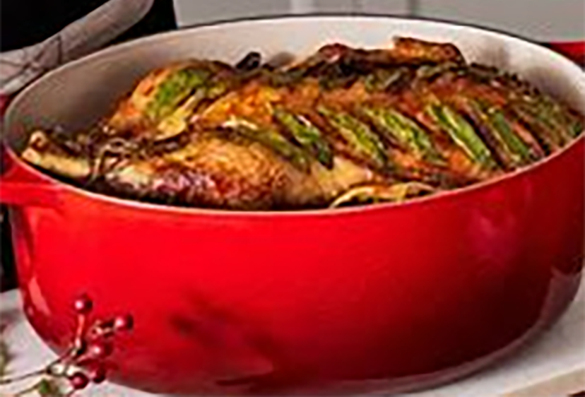 duck in a casserole dish topped with sage leaves