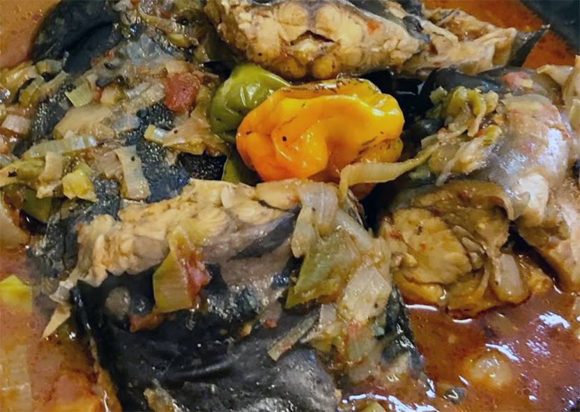 Cameroonian fish pepper soup topped with whole chillies and served in a bowl