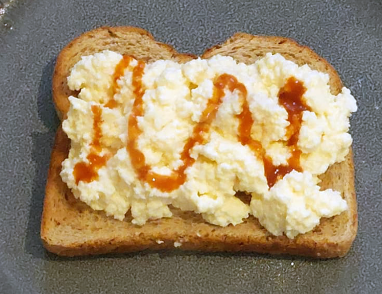scrambled eggs on toast topped with sriracha