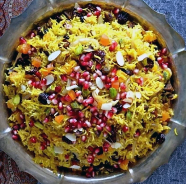 spiced rice on a steel plate garnished with pomegranate seeds, fruit and pistachios