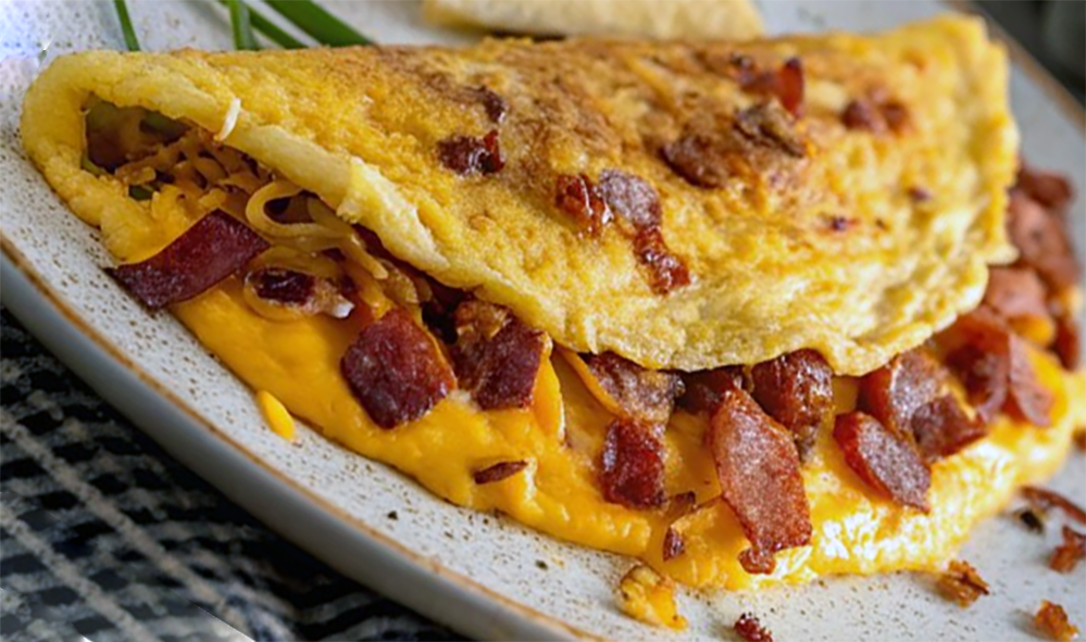 omelette containing chopped bacon served folded on a plate
