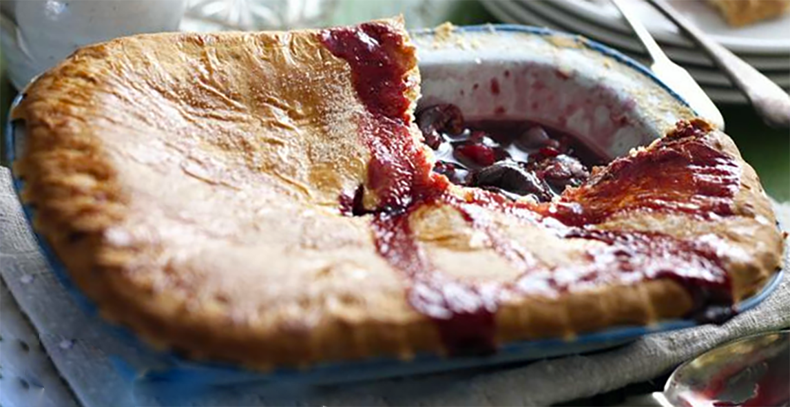 tart of barberries topped with pastry in a metal baking dish with a square removed