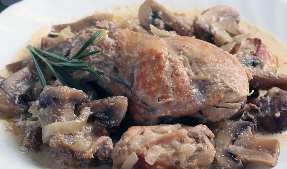 pigeons with mushrooms served on a plate with a sprig of rosemary