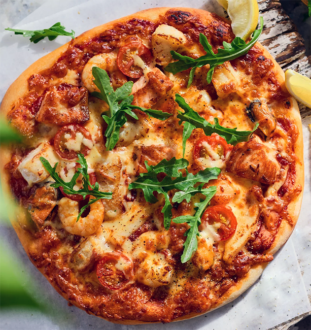 seafood pizza garnished with fresh rocket leaves