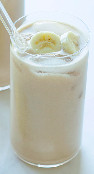 banana oat milk in a glass topped with banana slices