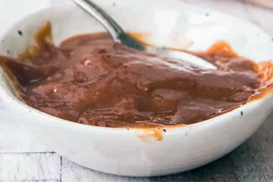plum jam sauce in a bowl with a spoon