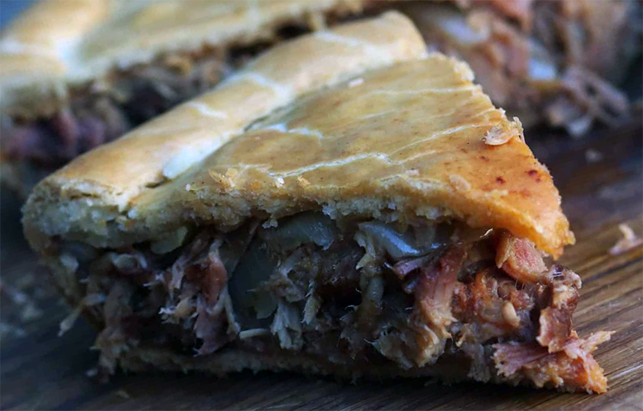 wedge of pork and chestnut pie with cranberries on a wooden chopping board