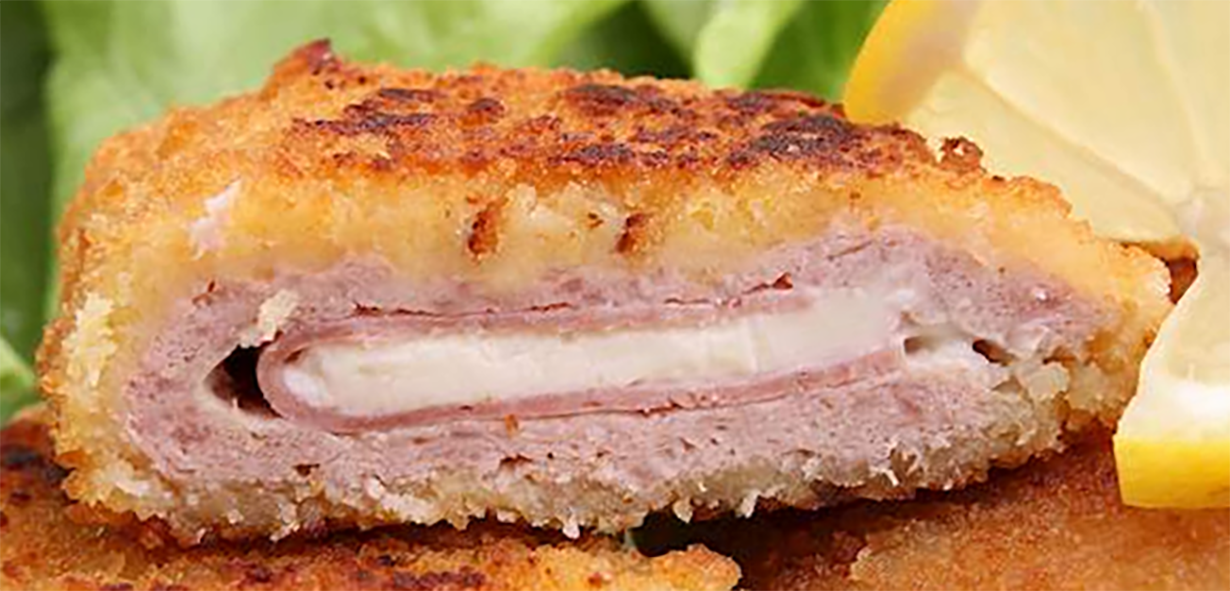 Pork schnitzel cordon bleu sliced in half to reveal the cheese and ham filling