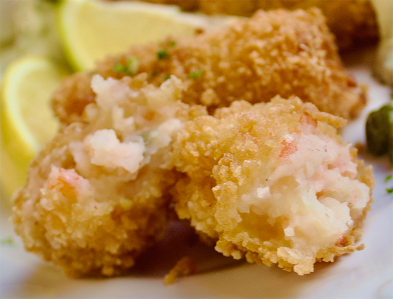 prawn croquettes on a plate with one split to reveal the filling