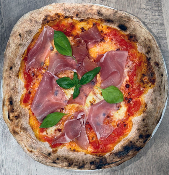 rustic style pizza topped with prosciutto and basil