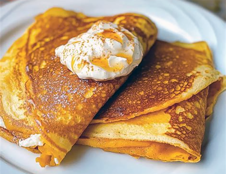 pumpkin flour pancakes folded and garnished with cream cheese on a plate