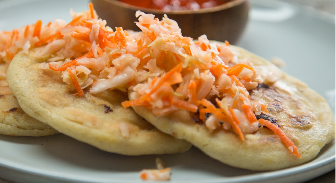 pork-filled pupusas on a plate topped with curtido