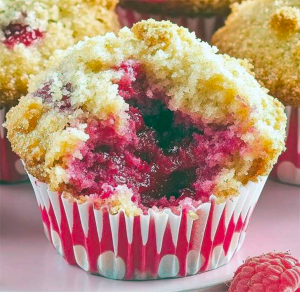 raspberry lemon muffin with streusel topping with a section removed to show the centre