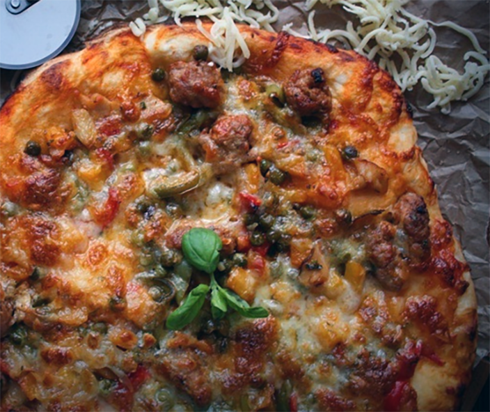 ratatouille and lentil pizza on a sheet of baking parchment with a pizza wheel