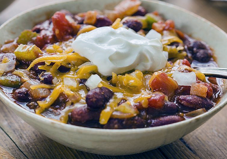 red kidney bean chili topped with cheese and sour cream in a bowl