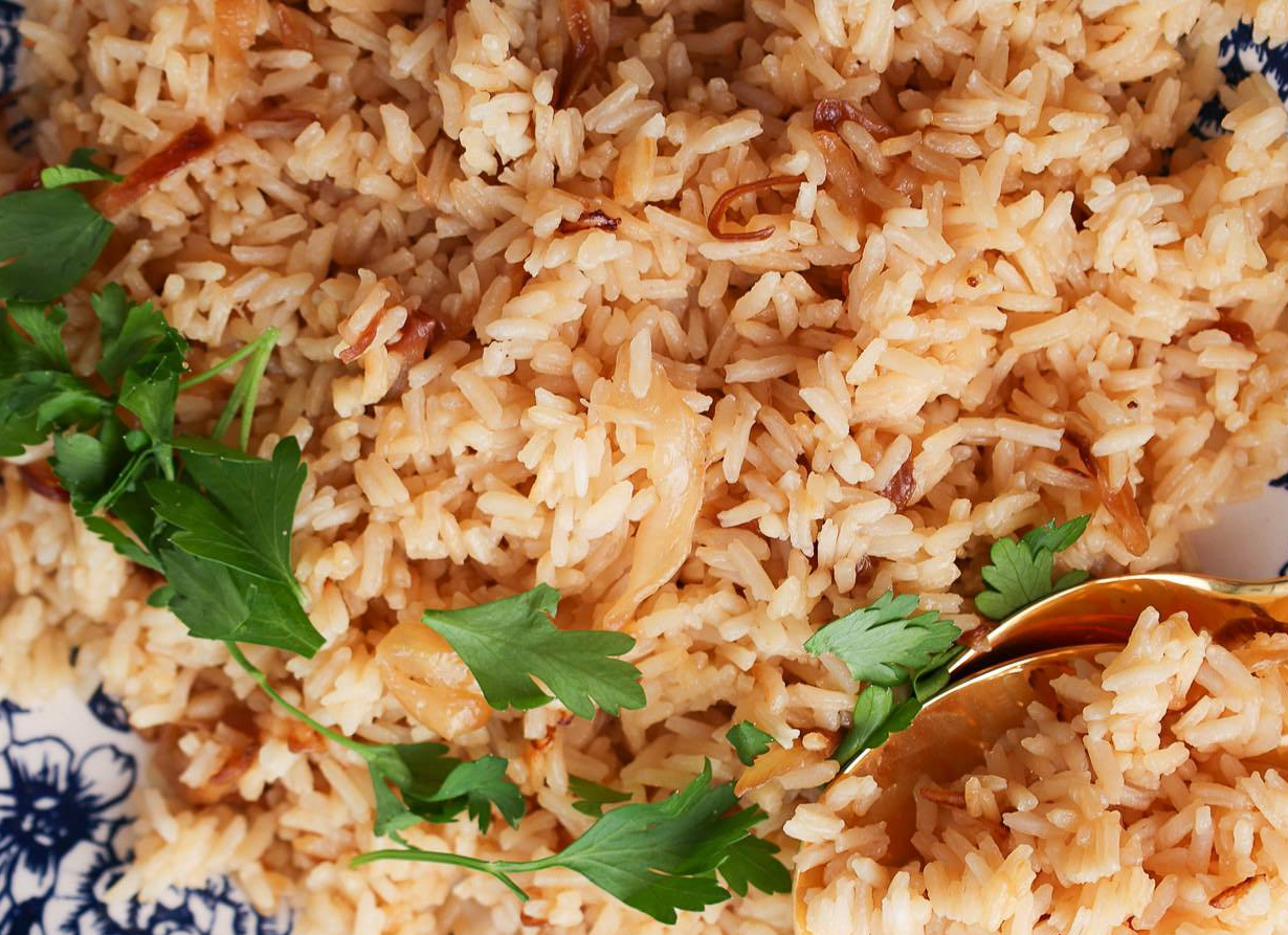 plate of rice cooked with oil and crisp-fried onions garnished with flat-leaf parsley