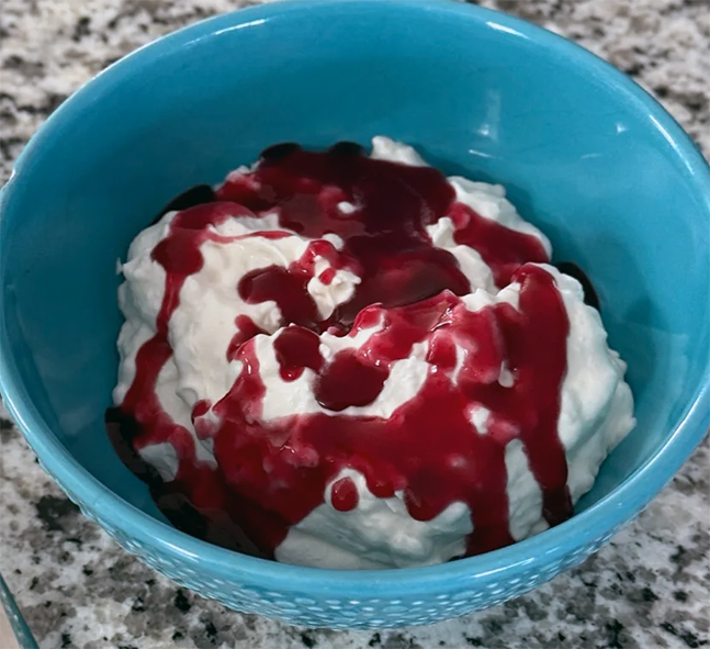 Norwegian riskrem, boiled rice cream served topped with a red berry compote in a blue bowl